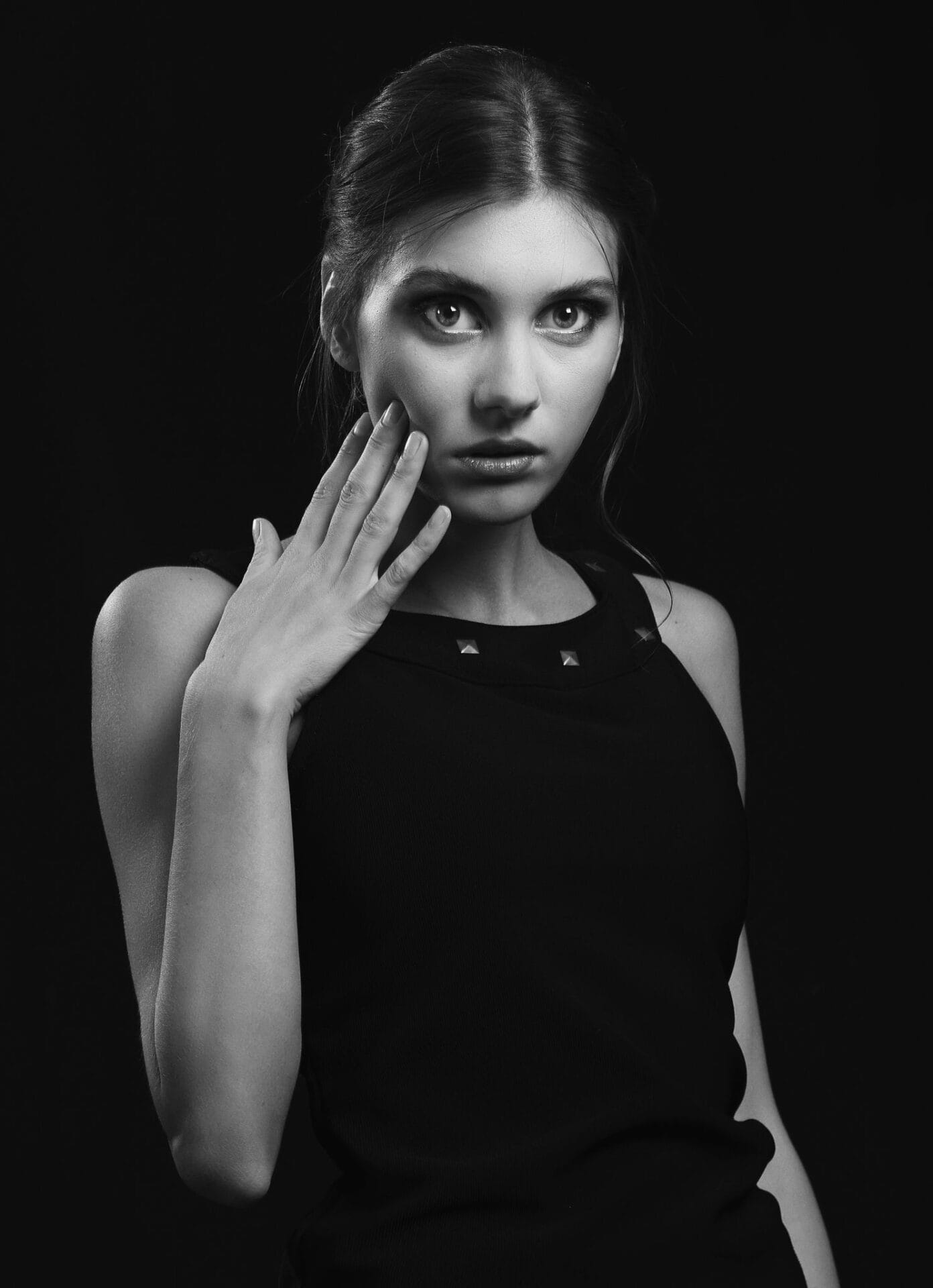 Striking black and white portrait of a young woman in a studio.